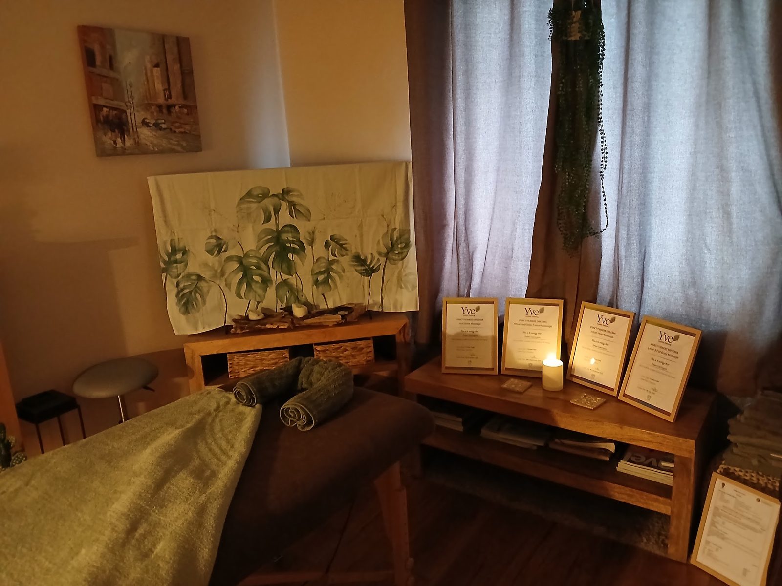 A corner of the room with framed certificates and a botanical throw